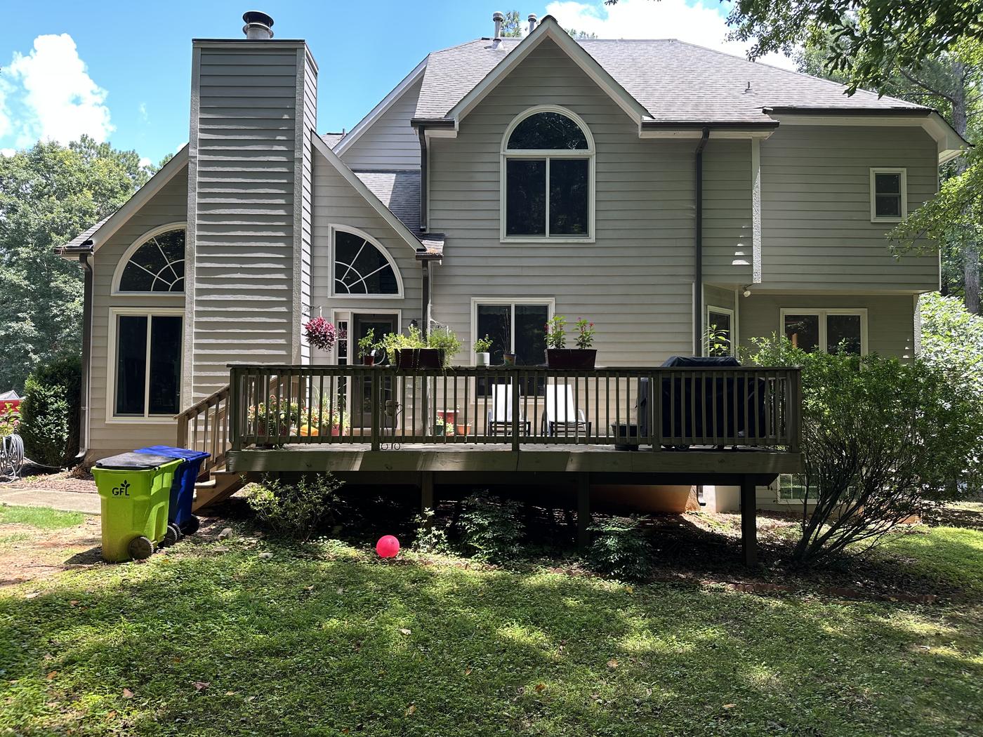 Before: the original weathered wood deck on the back of a two-story home